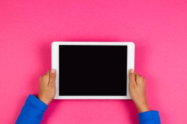 Tablet bilgisayarda pembe bir arka plan ile çocuk el.