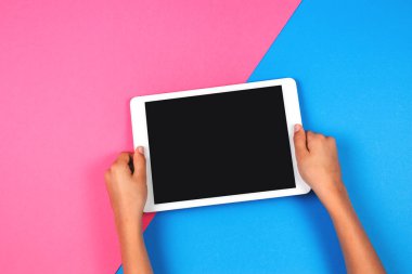 Tablet bilgisayarda pembe bir arka plan ile çocuk el.