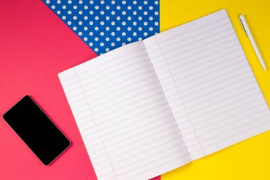 Hareket eden telefon, açık defter ve renkli arka plan üzerinde beyaz kalem