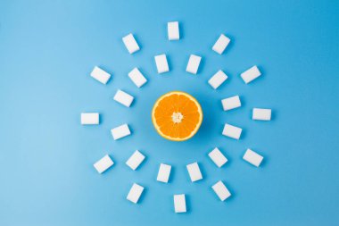 Taze turuncu ve mavi arka plan etrafında birçok beyaz şeker küpleri. Üstten Görünüm