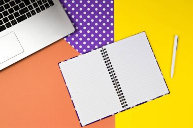 Dizüstü bilgisayar açık renkli arka plan üzerinde beyaz kalem ve kağıt defter.