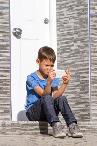 Junge mit Handy sitzt auf Treppe vor Tür — Stockfoto