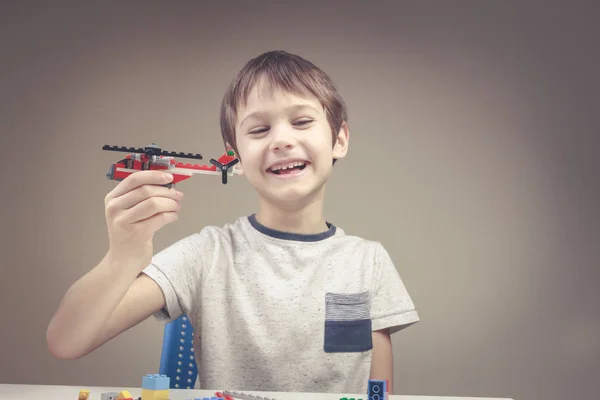 Niño sonriente jugando con ladrillos de construcción de plástico de colores en casa — Foto de Stock