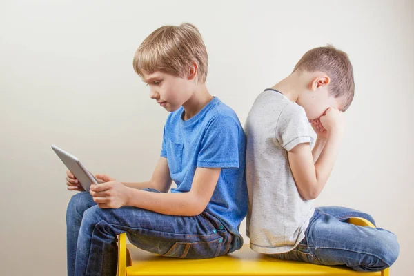 Compuer addiction. One boy using tablet and other kid rubbing tired eyes after long time playing game — Stock Photo, Image