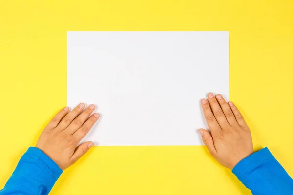 Kids hands with white blank paper card on yellow background Stock Image