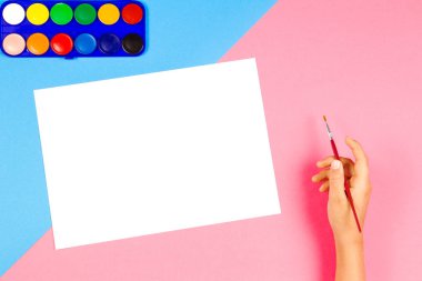 Çocuk el renkli arka plan üzerinde boya fırçası ve suluboya boya ile resim