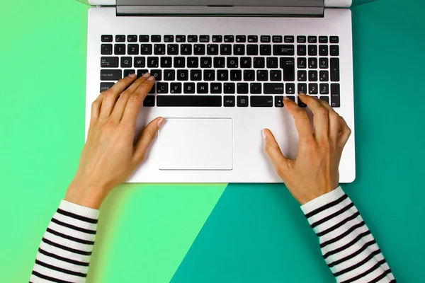 Kvinna händer att skriva på anteckningsboken klaviatur på färgstarka bakgrund — Stockfoto