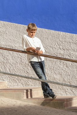 Açık havada merdiven korkuluk karşı smartphone ayakta yaslanmış çocukla.