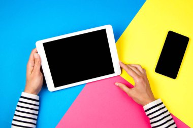 Tablet bilgisayar ve renkli arka plan üzerinde smartphone ile kadının el.