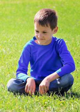 Yaz parkta yeşil çimenlerin üzerinde siting boy gülümseyerek