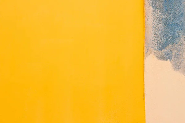 Fondo abstracto de la pared. Colorida pared amarilla comenzó a pintar con color azul — Foto de Stock