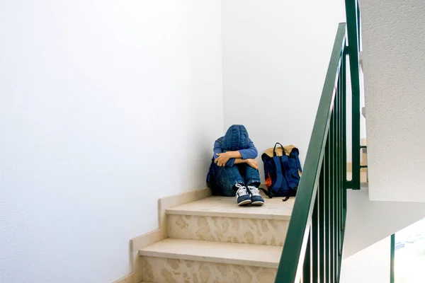 Trauriger Junge mit Rucksack sitzt allein in der Ecke im Treppenhaus — Stockfoto