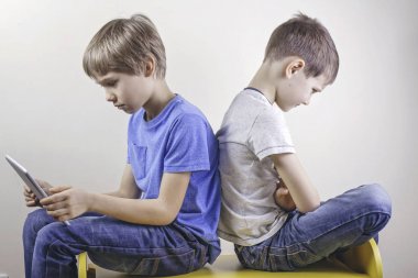 Bilgisayar bağımlılığı. Bir çocuk bir Tablet ve uzun süre oyun oynadıktan sonra kızgın oturan diğer çocuk kullanarak