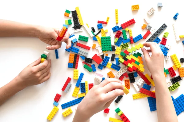 Vilnius, Litvanya - Nisan 2017. Çocukların elleri beyaz masada renkli lego bloklarıyla oynar..
