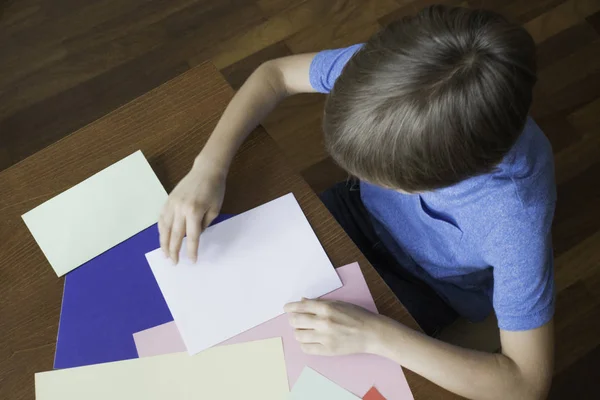 Menino faz cartão de saudação usando papel colorido — Fotografia de Stock