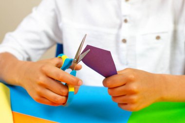 Renkli kağıt masada makasla kesme çocuk eller