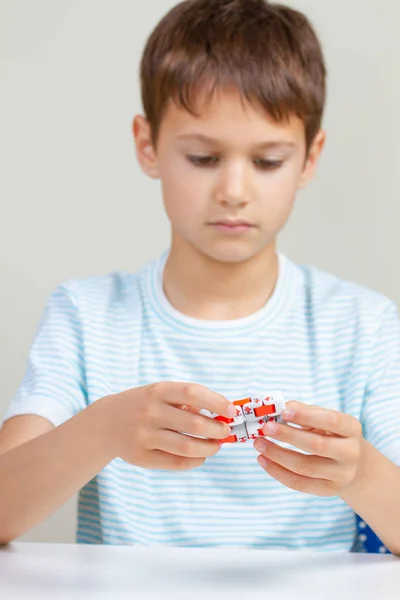 Pojke sitter vid bord och leker med fingrar antistress leksak — Stockfoto
