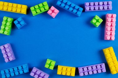 Çocuklar oyuncak çerçeve olarak mavi arka plan üzerinde renkli plastik inşaat blokları