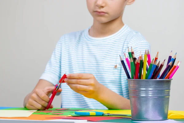 Mãos de criança cortando papel colorido com tesoura na mesa — Fotografia de Stock