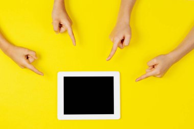 Birçok çocuk sarı arkaplanda tablet bilgisayarını işaret ediyor