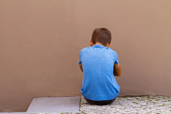 야외 벽에 뒤에 바닥에 앉아 슬픈 혼자 소년 — 스톡 사진