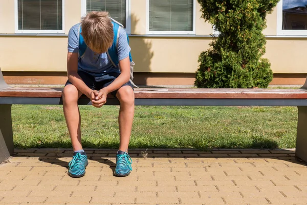 Unglücklicher trauriger Junge, der mit gesenktem Kopf in geschlossener Position sitzt. Mobbing in der Schule, Lernschwierigkeiten — Stockfoto