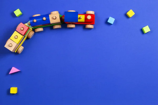 Spielzeugeisenbahn aus Holz mit bunten Blöcken auf blauem Hintergrund. Ansicht von oben — Stockfoto