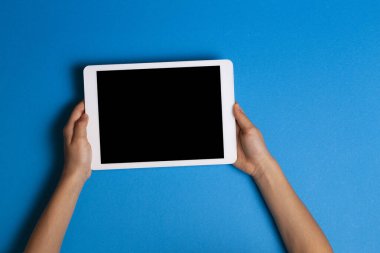 Çocuk elleri açık mavi arkaplanda beyaz tablet bilgisayarı tutuyor