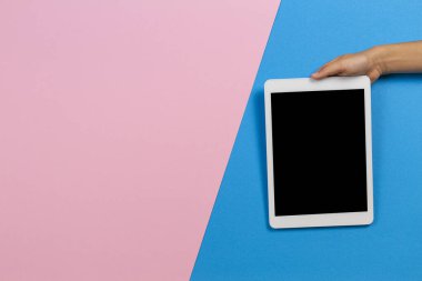 Çocuk elleri elinde dijital tablet bilgisayarla Pastel pembe ve açık mavi arkaplanda