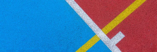 Kolorowe tło boisko sportowe. Widok z góry na czerwone i niebieskie pole gumowe ziemi z białymi i żółtymi liniami na zewnątrz — Zdjęcie stockowe