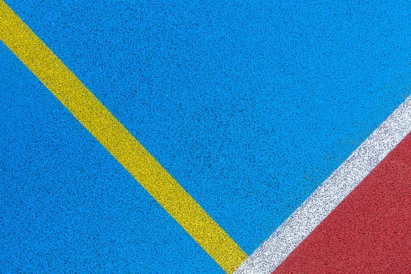 Colorful sports court background. Top view to red and blue field rubber ground with white and yellow lines outdoors