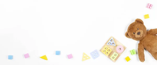 幼儿玩具横幅背景。 木制教育几何堆砌块形状的颜色识别拼图玩具，玩具熊和彩色块白色背景。 俯瞰，平铺 — 图库照片
