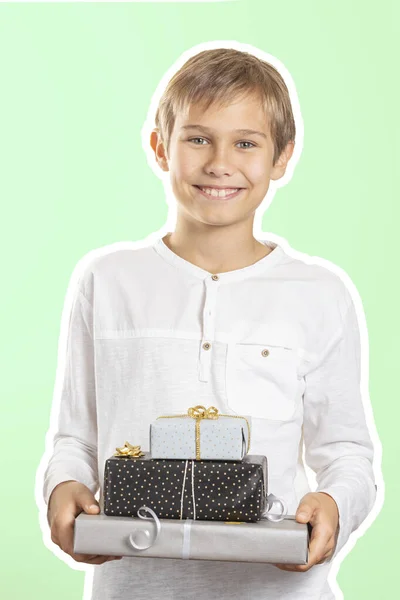 Niño feliz sosteniendo papel de pila envuelto en cajas de regalo regalo. Estilo collage revista con fondo de color verde claro. Vacaciones, concepto de Navidad —  Fotos de Stock