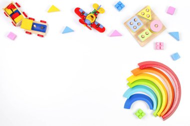 Bebek çocukların oyuncak geçmişi. Tahta eğitici geometrik istifleme blokları oyuncaklar, gökkuşağı, uçak, tren ve beyaz arka planda renkli bloklar. Üst manzara, düz uzanma
