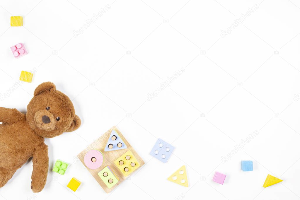 Baby kids toys background. Wooden educational geometric stacking blocks shape color recognition puzzle toy, teddy bear and colorful blocks on white background. Top view, flat lay