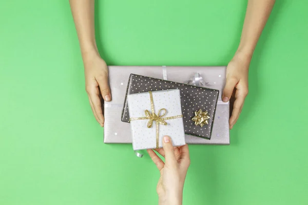 Hands give and take presents boxes over light green background. Christmas, New Year, holidays, birthday concept