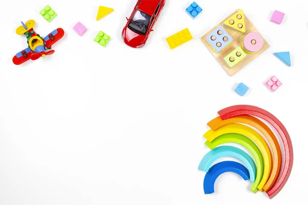 Bebê crianças brinquedos fundo. O empilhamento geométrico educacional de madeira bloqueia o brinquedo, o arco-íris, o avião, o carro e os blocos coloridos no fundo branco. Vista superior, flat lay — Fotografia de Stock