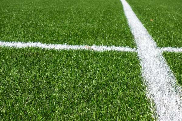 Zielony syntetyczny trawa piłka nożna boisko sportowe z białymi paskami linii — Zdjęcie stockowe
