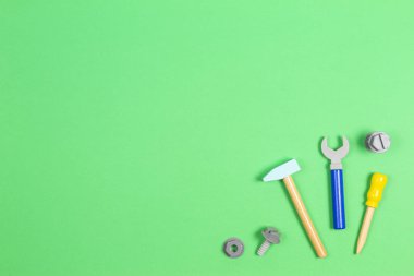 Tahta çocuk oyuncakları tornavida, kerpeten, civata, fındık ve açık yeşil arka plandaki diğer inşaat aletleri. Üst görünüm