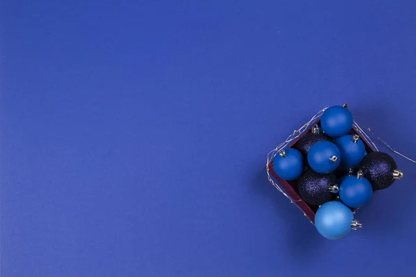 Bolas de bolas de Navidad azul y guirnalda en la caja sobre fondo azul. Vista superior — Foto de Stock