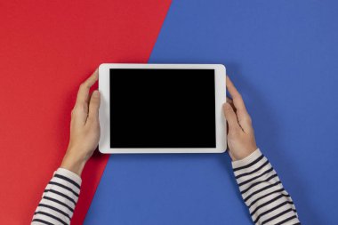 Mavi ve kırmızı arka planda tablet bilgisayarı olan kadın eller. Üst görünüm