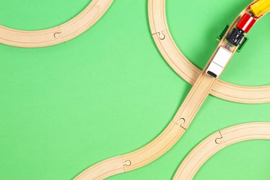 Baby kid toys background. Toy train and wooden rails on light green background. Top view clipart