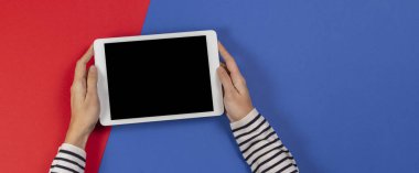 Mavi ve kırmızı arka planda tablet bilgisayarı olan kadın eller. Üst görünüm