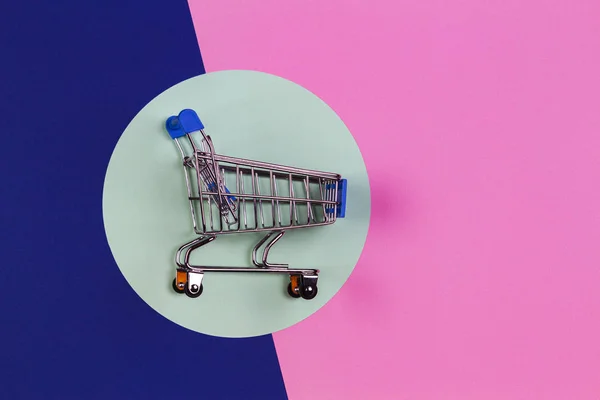 Mini winkelwagen op lichtgroene, roze en blauwe marine achtergrond. Online winkelen, kopen, koop, korting concept — Stockfoto