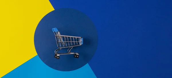 Mini shopping trolley cart on red yellow navy blue background. Online shopping, buy, sale, discount concept — Stockfoto