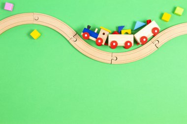 Renkli blokları olan tahta oyuncak tren ve açık yeşil arka planda ahşap demiryolu.