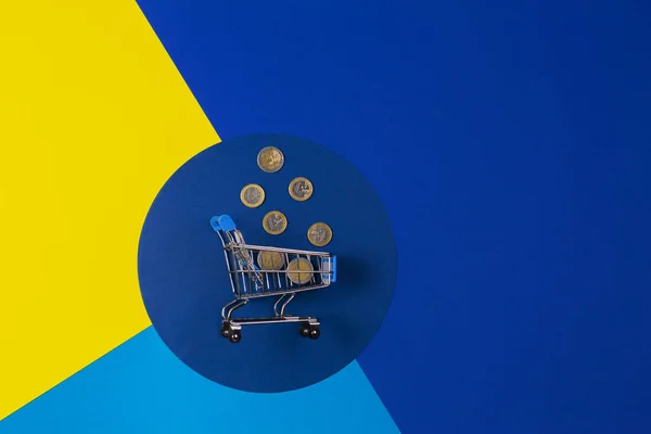 迷你购物车与欧元硬币的黄色海军蓝色背景。 网上购物、购买、销售、储蓄、折扣概念 — 图库照片