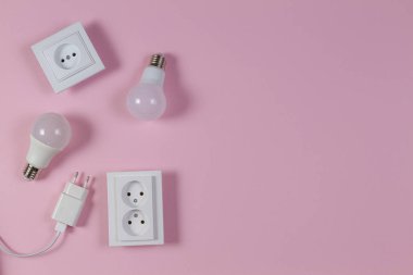 Beyaz elektrik prizleri, elektrik prizleri, açık pembe arka planda ampuller. Üst görünüm