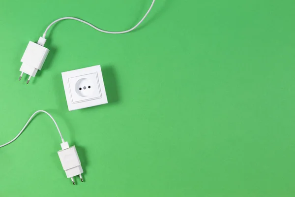 White electrical power socket and power plugs on light green background. Top view