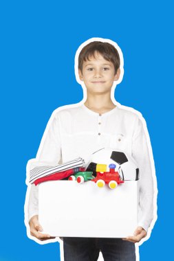 Bağış konsepti. Çocuk bağış kutusunu kıyafetlerle, kitaplarla, okul gereçleriyle ve oyuncaklarla tutuyor. Dergi kolaj biçimi mavi arkaplan